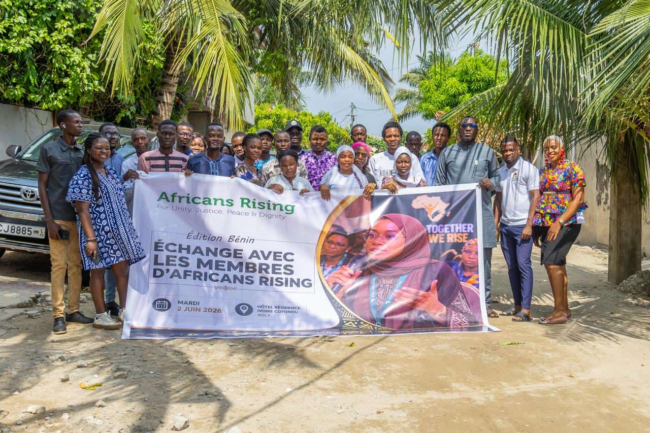 Benin 2 - Africans Rising - Africans Rising Group of people posing outdoors under palm trees, holding a banner for Africans Rising.