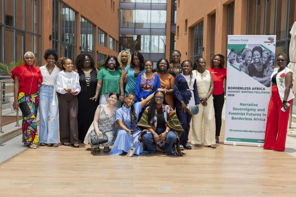 Diverse group of women posing together outdoors, smiling, with a tall banner reading 'Africans Rising' on the right.