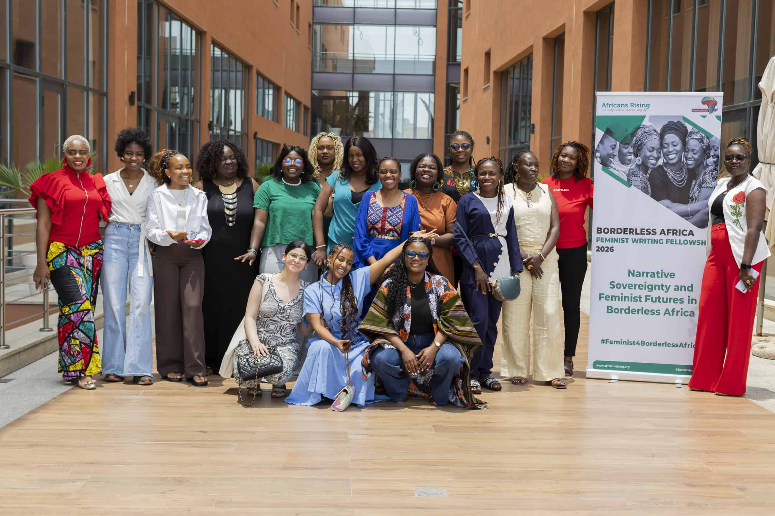 Feminist Fellowship 11_1 - Africans Rising - Africans Rising Diverse group of women posing together outdoors, smiling, with a tall banner reading 'Africans Rising' on the right.