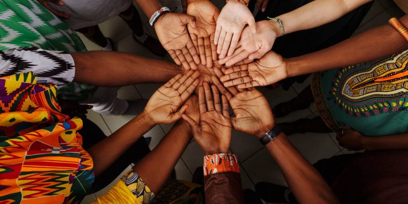 Palms up hands of a happy group of multinational African, Latin American and European people who stay together in a circle.